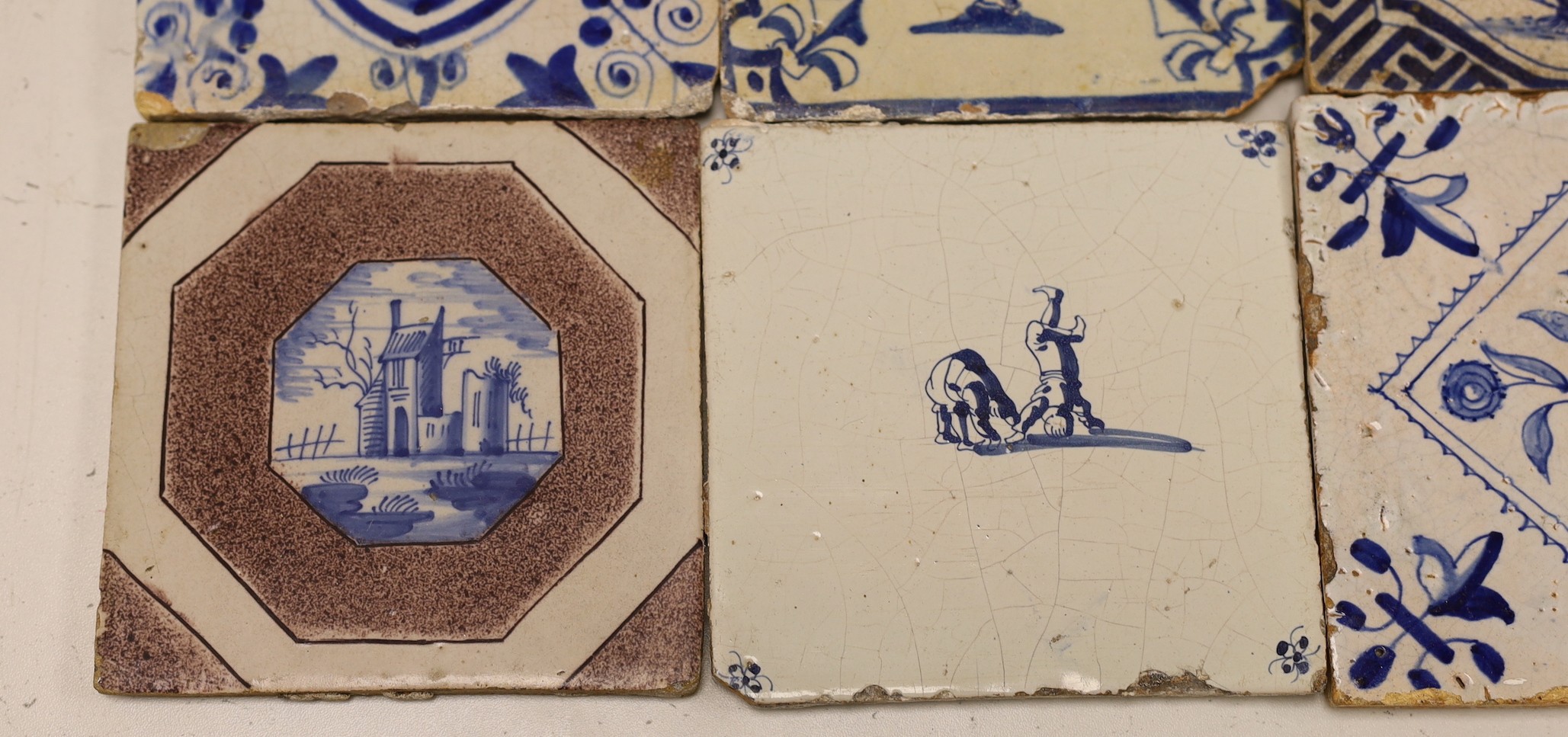 Four mid 17th century Delft blue and white ‘urn of flowers’ tiles, and an 18th century Delft ‘acrobats’ tile and blue and manganese ‘landscape’ tile (6)